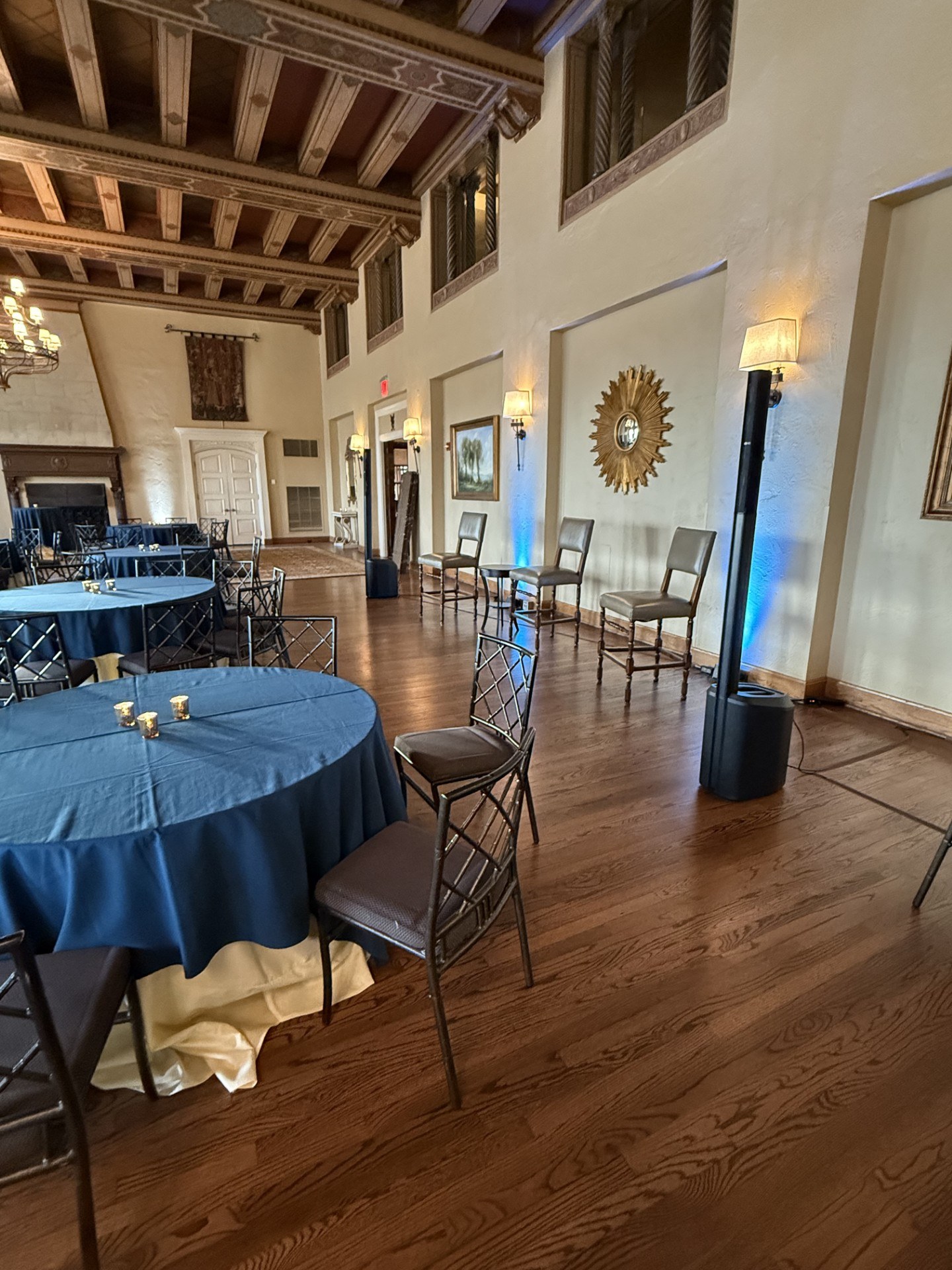 Historic event room with guest tables, seating and blue uplighting